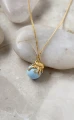 Pozłacany naszyjnik ośmiornica z błękitną perłą Swarovski na jasnych kamieniach.png