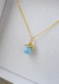 Pozłacany naszyjnik ośmiornica z błękitną perłą Swarovski w pudełku ISSI.png