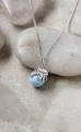 Srebrny naszyjnik ośmiornica z błękitną perłą Swarovski na jasnych kamieniach.png