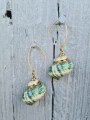 Wiszące kolczyki TURQUOISE SEASHELLS z zielono-turkusowych muszli na jasnym drewnianym tle.png